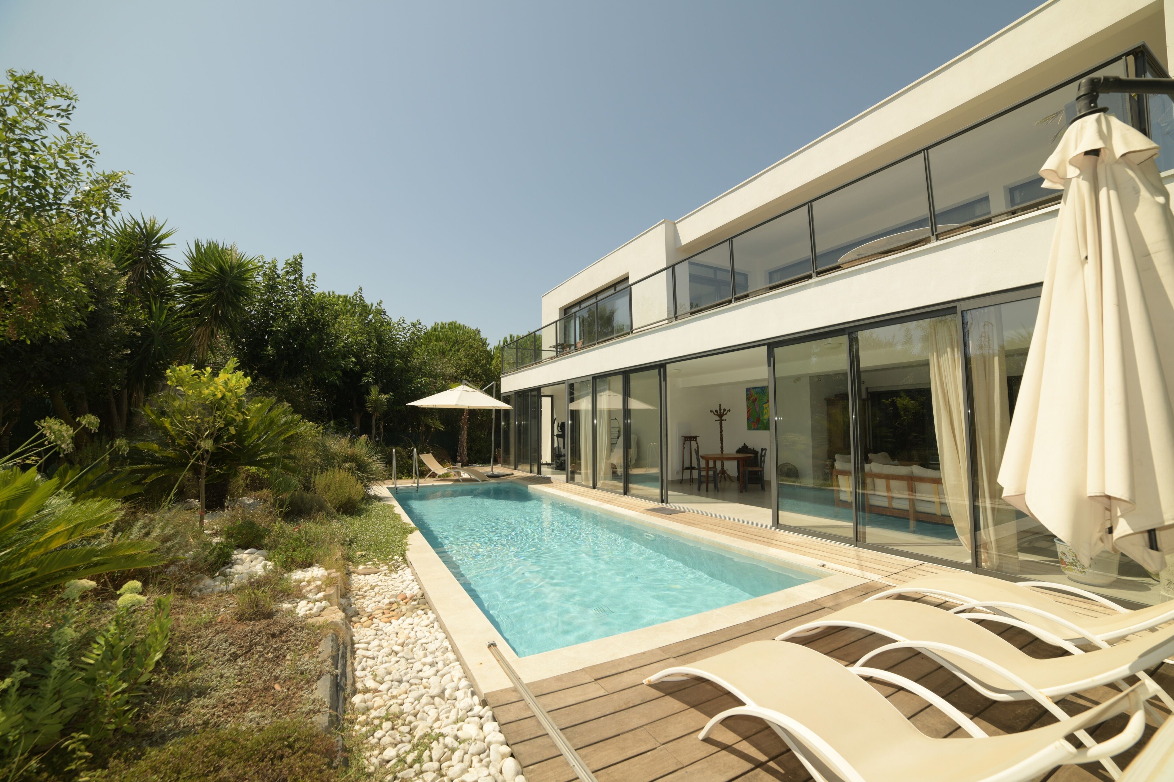 A modern house with a swimming pool, outdoor furniture, and lush greenery.