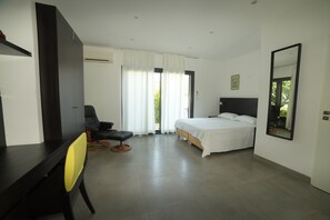 A hotel room with a bed, a desk, a chair, and a large mirror.