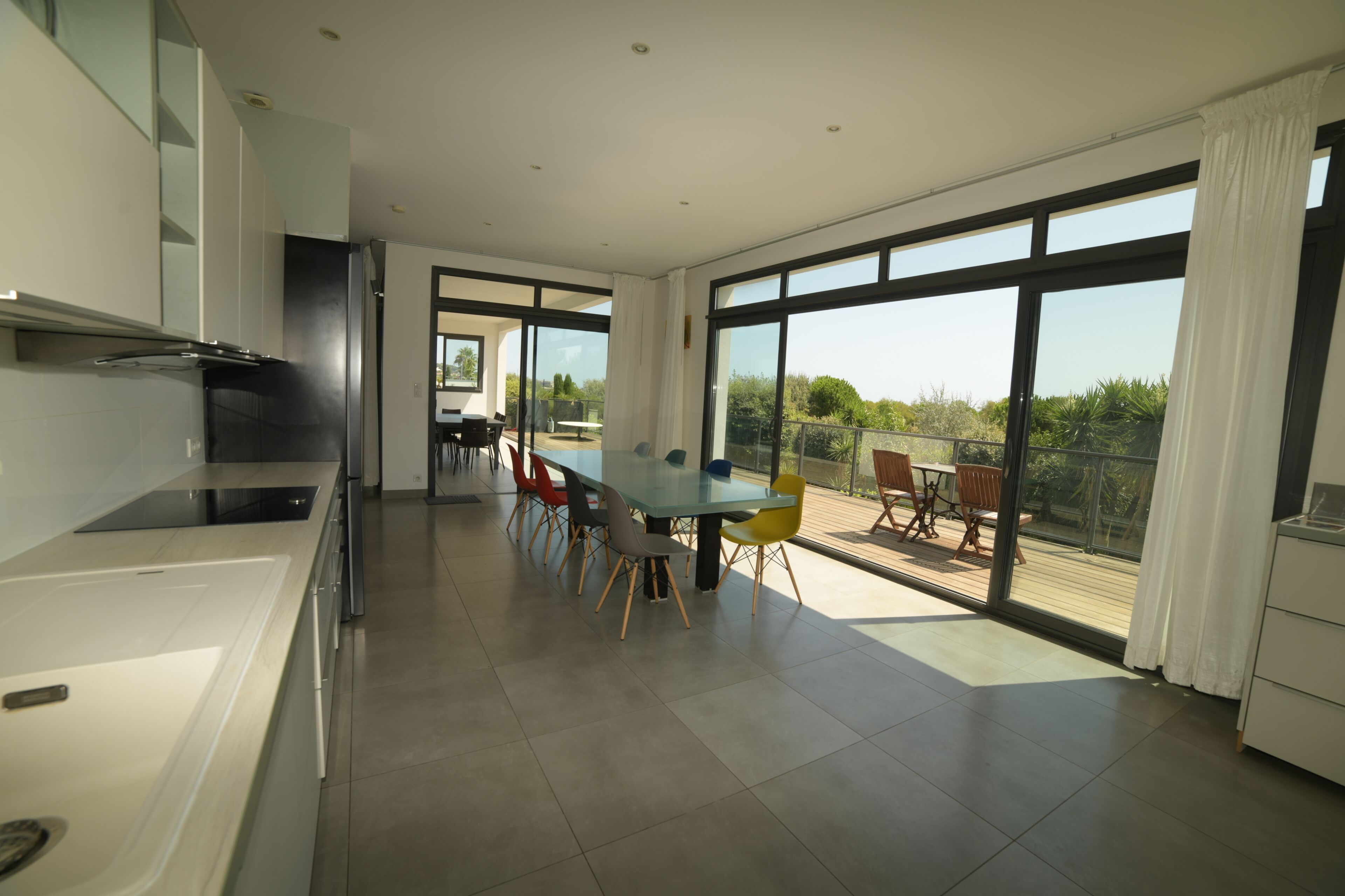 Une cuisine moderne avec un coin repas, de grandes fenêtres et une vue sur la verdure.