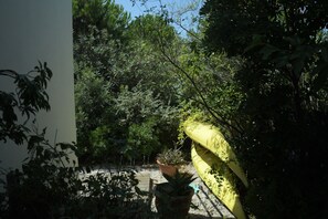 A garden with dense foliage, a yellow umbrella, and a potted plant.
