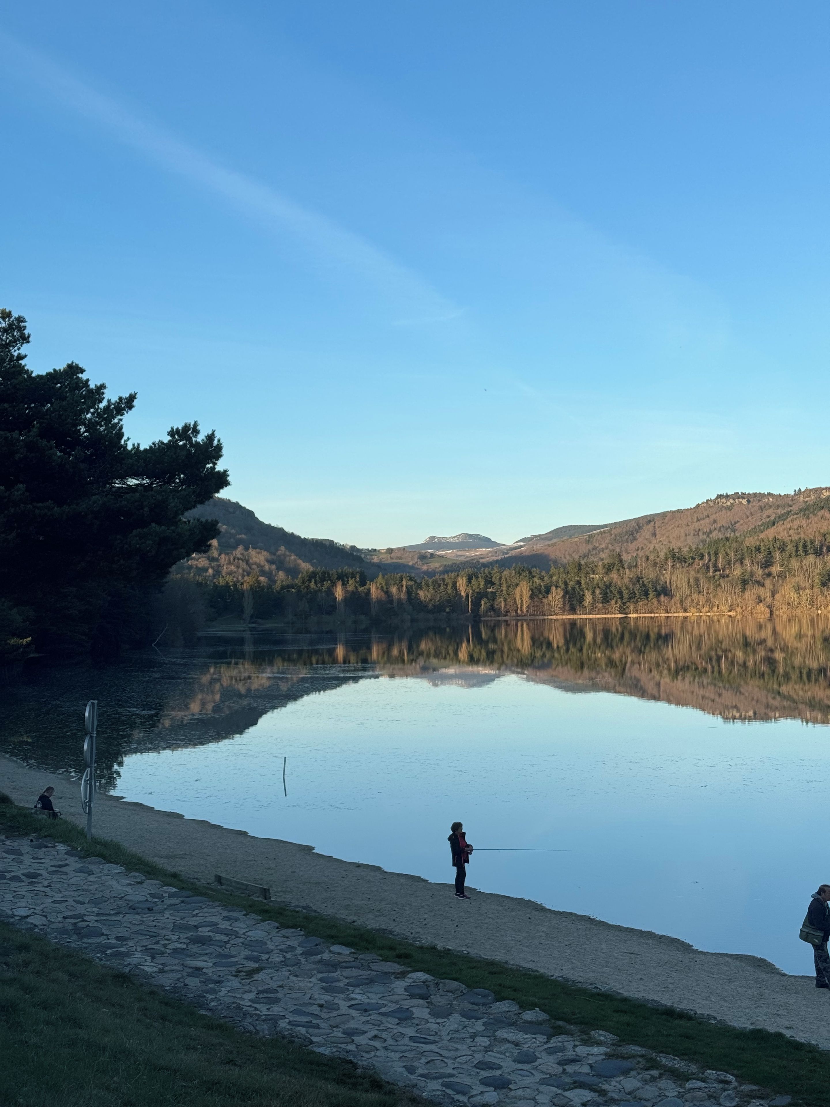 A calm lake with a stone path leading to a wooden dock.