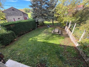 A stone building with a red door, a grassy yard, and a wooden picnic table.