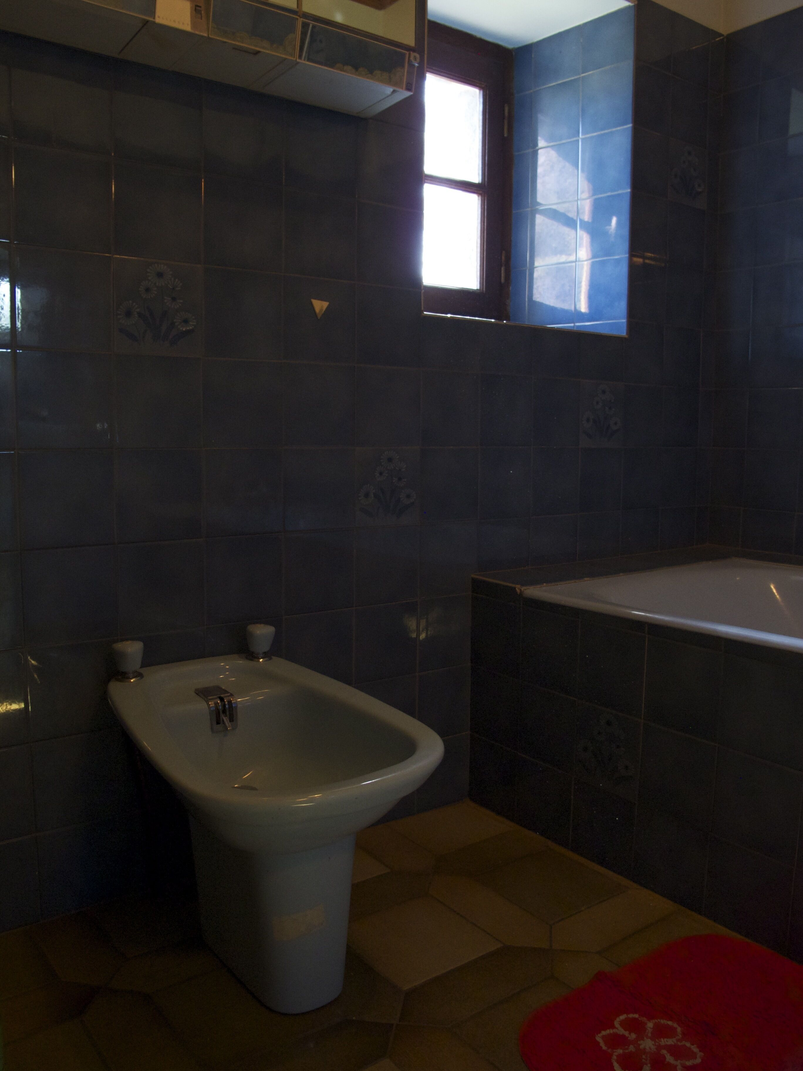 A bathroom with a bidet, a bathtub, and a window.