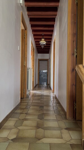 A hallway with a tiled floor, wooden doors, and a hanging light fixture.