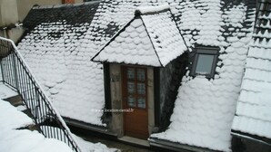 Een gebouw bedekt met sneeuw, met een hellend dak, een klein raam en een deur.
