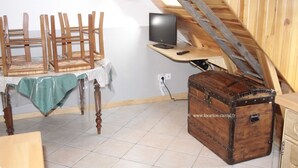 Een kamer met een houten tafel, stoelen, een televisie en een koffer.
