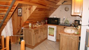Een keuken met houten kastjes, een magnetron, een koffiezetapparaat en een spoelbak.