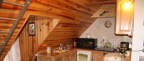 A kitchen with wooden cabinets, a microwave, a coffee maker, and a sink.