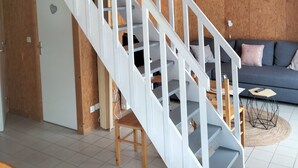 Un intérieur à plusieurs niveaux, avec un escalier blanc, un canapé et une petite table.