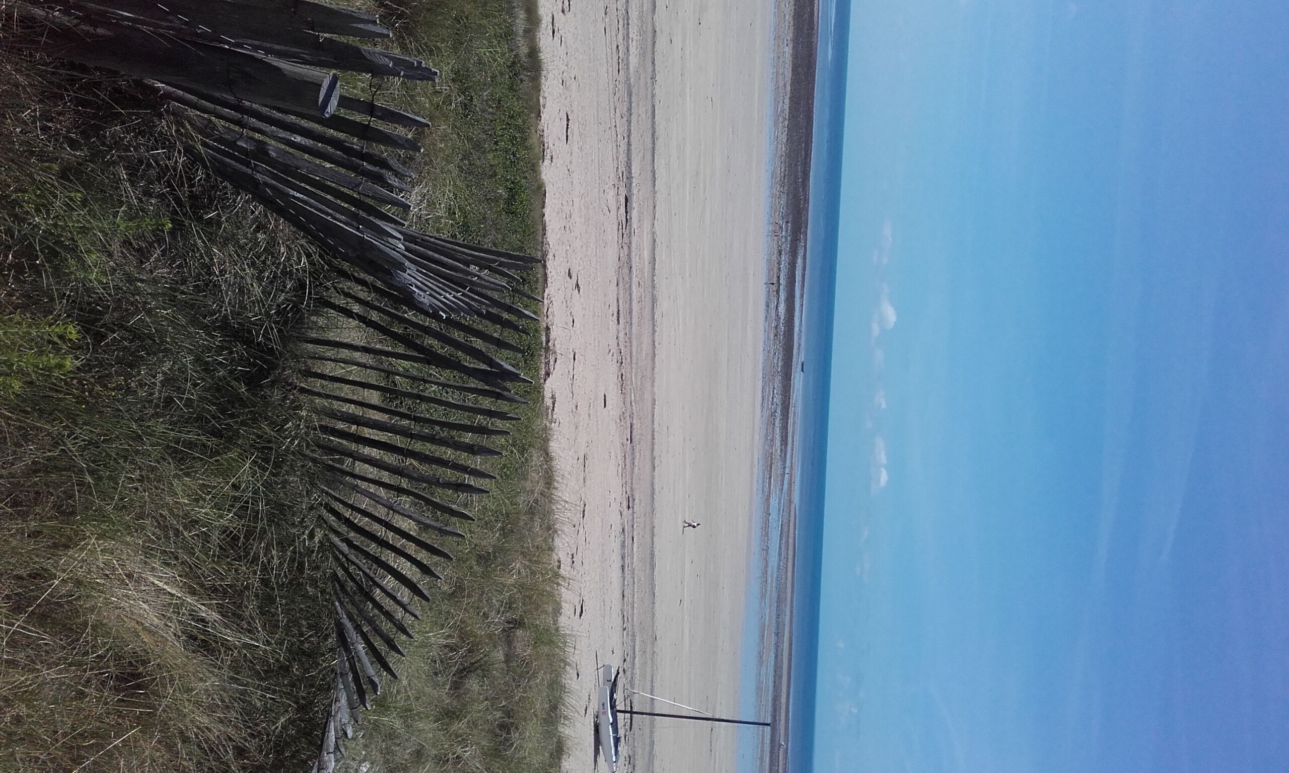 A beach with a wooden fence and a clear sky.