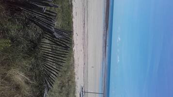 A beach with a wooden fence and a clear sky.