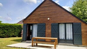 Un bâtiment en bois avec un toit à deux versants, un banc devant et une haie sur le côté gauche.