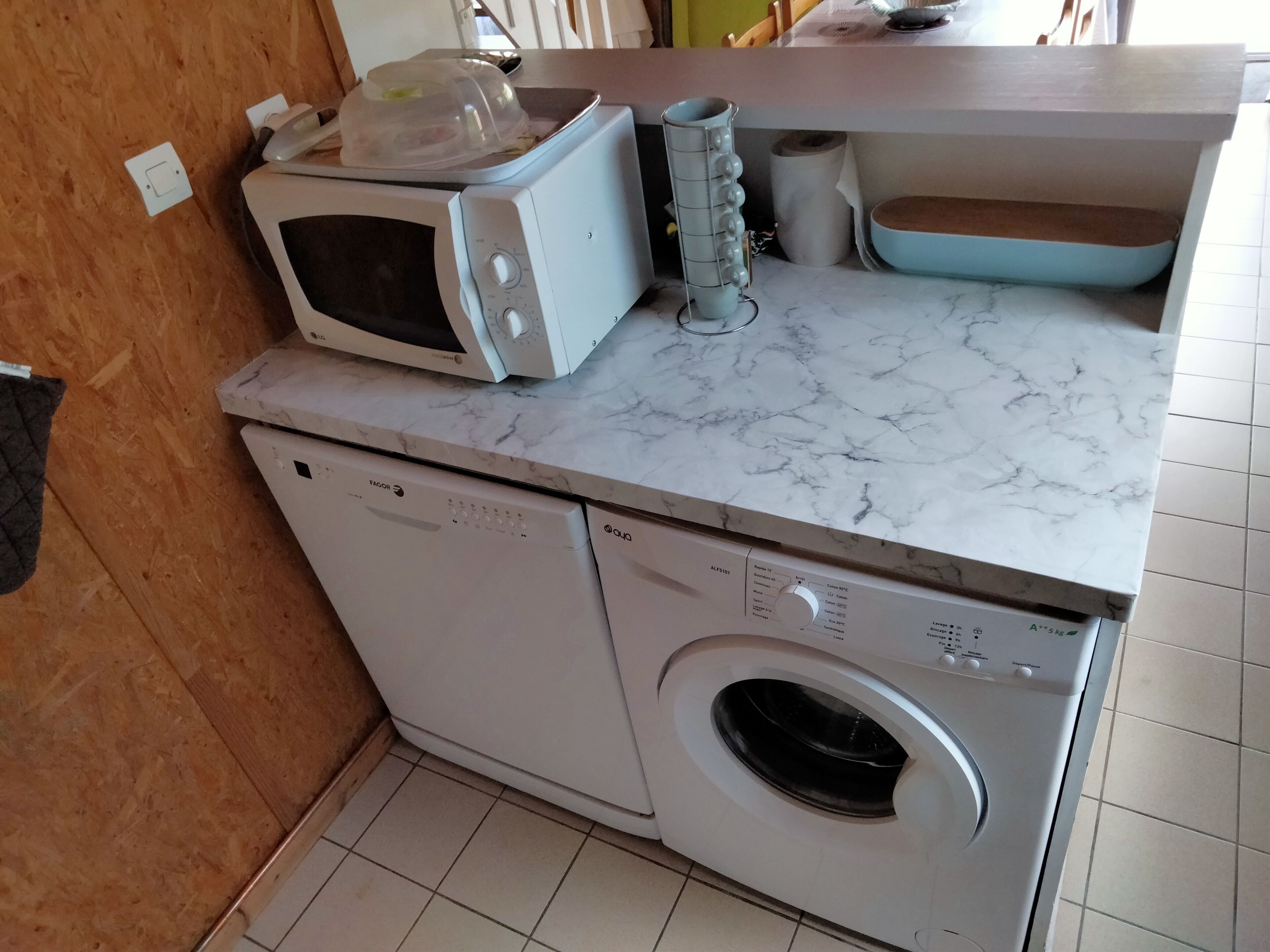 A compact kitchen with a microwave, a washing machine, and a sink.