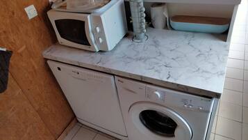 A compact kitchen with a microwave, a washing machine, and a sink.