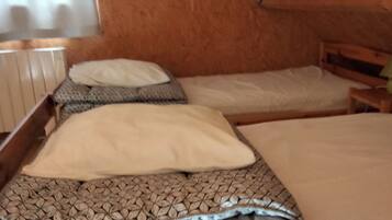 Un pequeño y acogedor dormitorio en ático con techo inclinado de madera, dos camas individuales con ropa de cama estampada y un radiador a la izquierda.