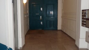 Un couloir avec une porte bleu foncé, un interrupteur et une fente pour le courrier dans le mur.
