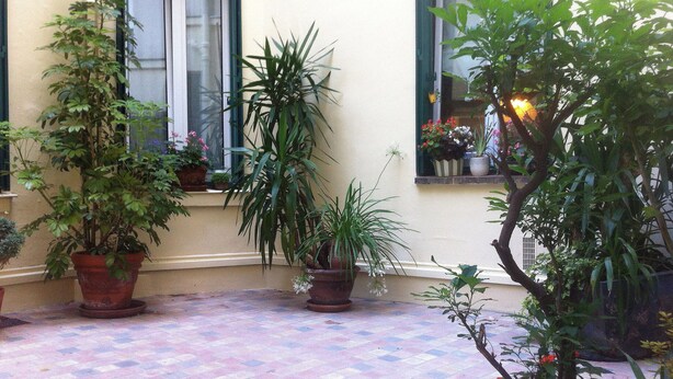 Une cour intérieure agrémentée de plantes en pot et dotée d’un sol carrelé.