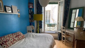 Une chambre à coucher avec un lit, un bureau et une chaise. Il y a une fenêtre donnant sur l’extérieur.
