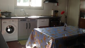 Une cuisine compacte équipée d’un lave-linge, d’un évier et d’une table recouverte d’une nappe.