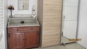 Une pièce comprenant un meuble en bois, un miroir, une petite statue et une armoire blanche.