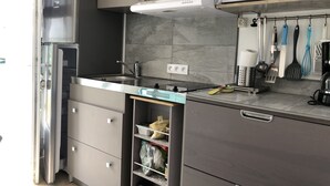 A modern kitchen with a built-in microwave, stainless steel appliances, and a countertop with various utensils. - Large house in Sernhac (Sernhac)