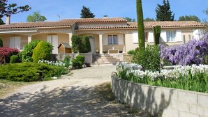 A two-story house with a tiled roof, a front porch, and a gravel driveway leading to a set of stairs. - Large house in Sernhac (Sernhac)