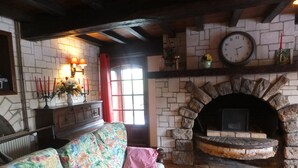 A cozy living room with a stone fireplace, a sofa with floral upholstery, and a wooden coffee table.