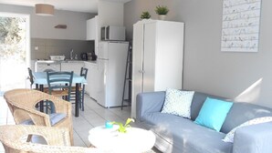 Un espacio habitable compacto con comedor, kitchenette y un sofá con cojines.