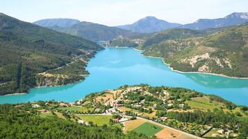 Un paisaje montañoso con un lago, rodeado de vegetación y un pequeño asentamiento.