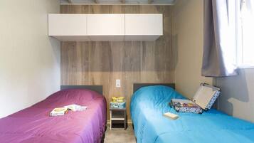 Une petite chambre, de taille modeste, comprenant deux lits simples, une petite table et une armoire.