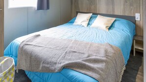 Ein Schlafzimmer mit einem Bett, einem Fenster mit Vorhängen, einer Decke mit Holzbalken und Einbauschränken über dem Bett.