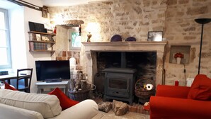 Una sala de estar acogedora con pared de piedra, chimenea, televisor y mobiliario rojo.