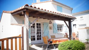 A house with a covered patio, a wooden gate, and a small garden.