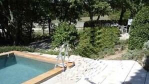 Ein rechteckiger Pool mit einer Holzterrasse und einer Metallleiter.