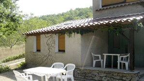 Eine Terrasse mit Tisch und Stühlen, eine Steinmauer und ein Gebäude mit einem Ziegeldach.