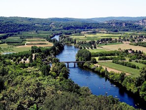 A river with a bridge, surrounded by lush greenery and fields. - Quiet stone house (Carennac)