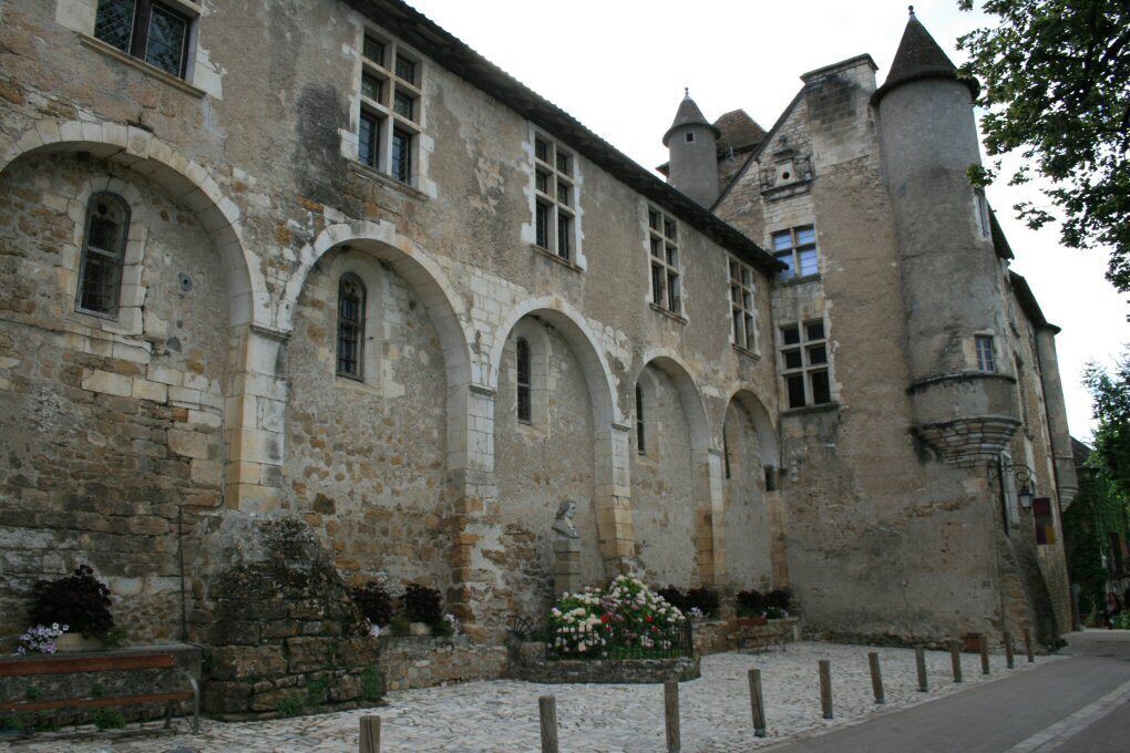 Un edificio histórico de piedra con ventanas de arco y una torre.