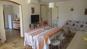 A dining area with a table set for four, a television, and a sofa in the background. - Air conditioned apartment, fully equipped, nice, for a good holiday. WIRELESS.   (SAINT-AYGULF)