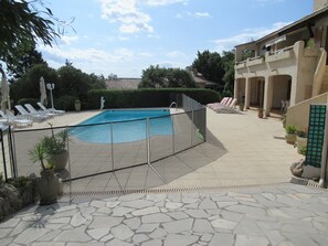 A swimming pool with a tiled deck, surrounded by lounge chairs and potted plants. - Air conditioned apartment, fully equipped, nice, for a good holiday. WIRELESS. (SAINT-AYGULF)