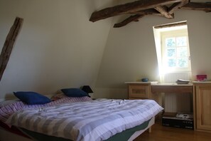 Une chambre à coucher avec un lit, un bureau, une fenêtre et un radiateur.