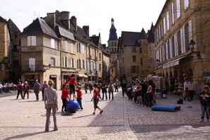 Une place historique au cœur d’une ville européenne, avec ses rues pavées, ses bâtiments traditionnels et son imposant clocher d’église.