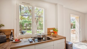 Una cocina moderna con encimera de madera, estufa y ventana con vistas a un jardín.