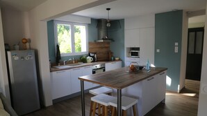 A modern kitchen with a wooden island, white bar stools, and a built-in oven.