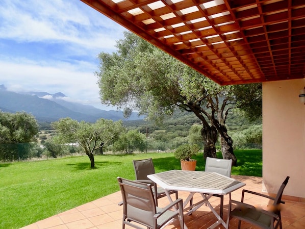 A patio with a table and chairs, overlooking a green landscape and mountains. - Large villa, panoramic sight on mountain, 3km beach and golf (Occhiatana)