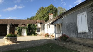 Ein traditionelles Gebäude mit einem Kieshof, einem Steingartenbeet mit Blumen und einem Hund in der Nähe des Eingangs.