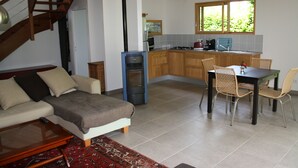 Une cuisine moderne avec des meubles en bois, un coin repas avec des chaises en osier et un escalier menant à un étage supérieur.