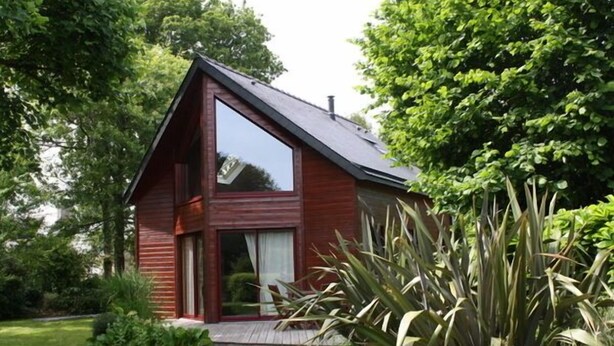 Une maison moderne avec un toit en pente, une grande baie vitrée et une façade en bois.