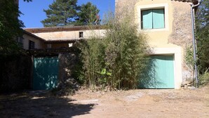 Un bâtiment rustique avec une façade en pierre, une petite fenêtre et une porte verte.