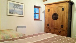 Une chambre à coucher avec un lit, une fenêtre, un radiateur et une armoire en bois.