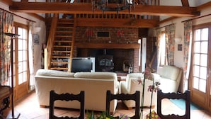 A cozy living room with a fireplace, wooden beams, and a television. - Gîte in the Bay of Somme (Pendé)